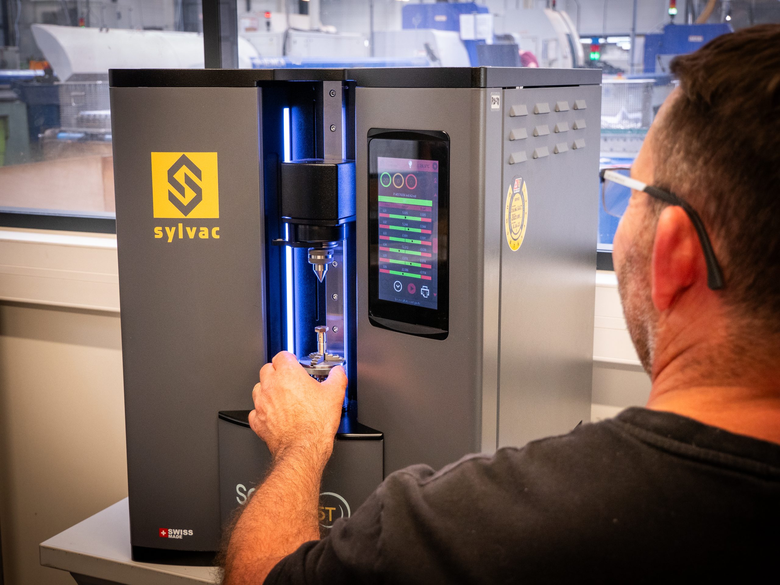 Homme déposant une pièce dans une machine de vérification Sylvac Scan S25T