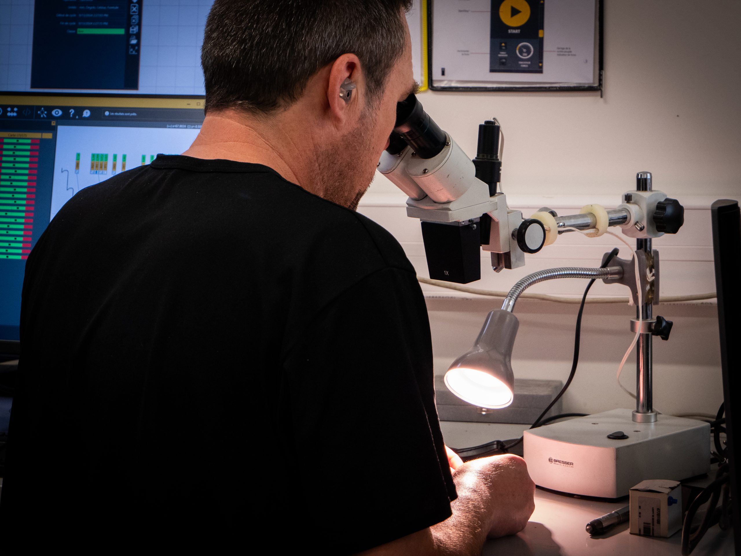Homme faisant la vérification d'une pièce avec un microscope adapté